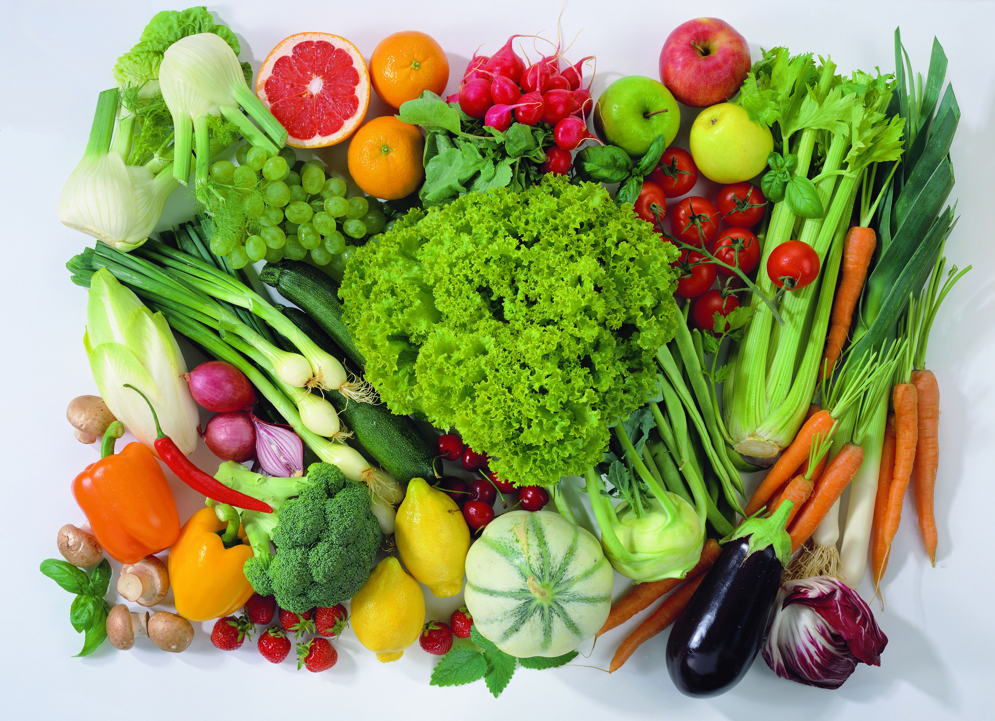 Vários legumes e verdruas sobre uma mesa vistos de cima.